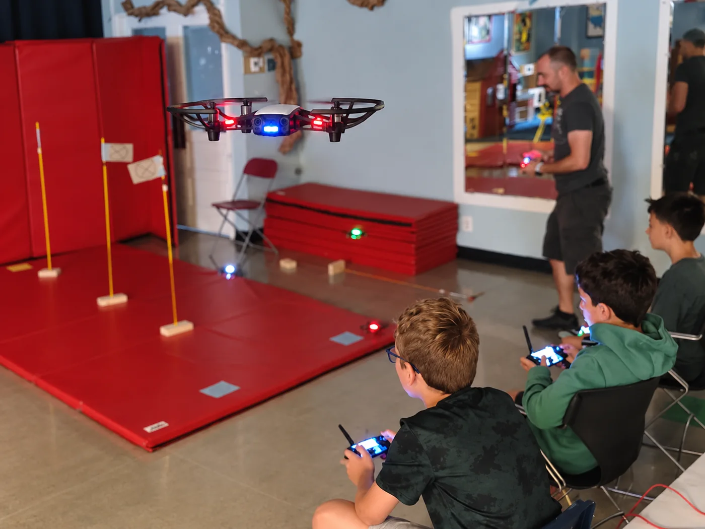 Young learners piloting drones through an indoor obstacle course