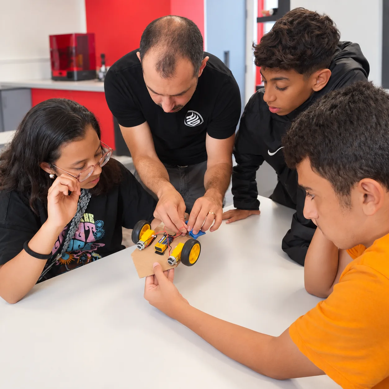 An instructor helping learners connect robot electronics