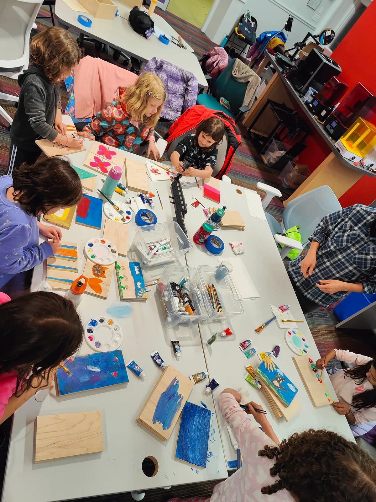 Children painting wooden projects together around a table