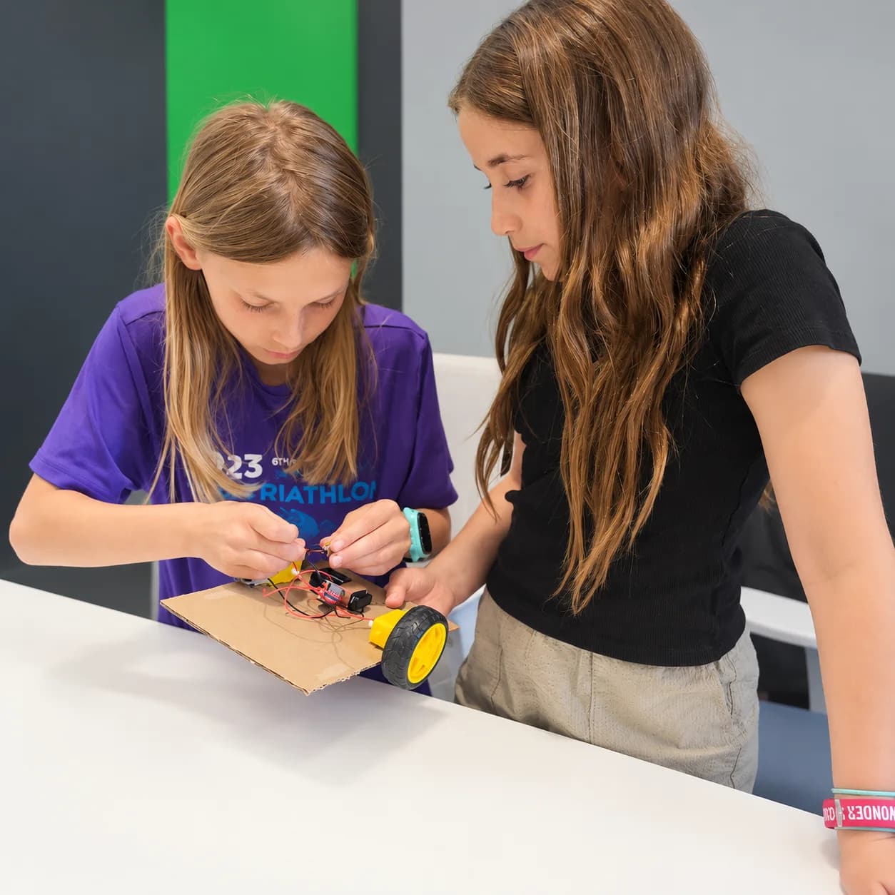 Two young makers wiring a cardboard robot together