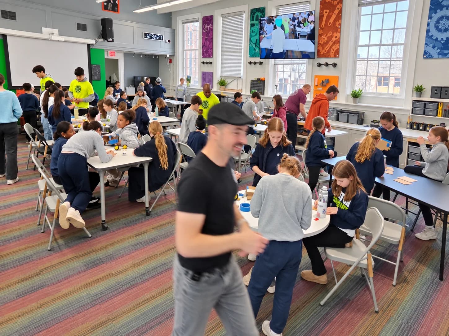 Instructors supporting a large group of learners building robots at workshop tables