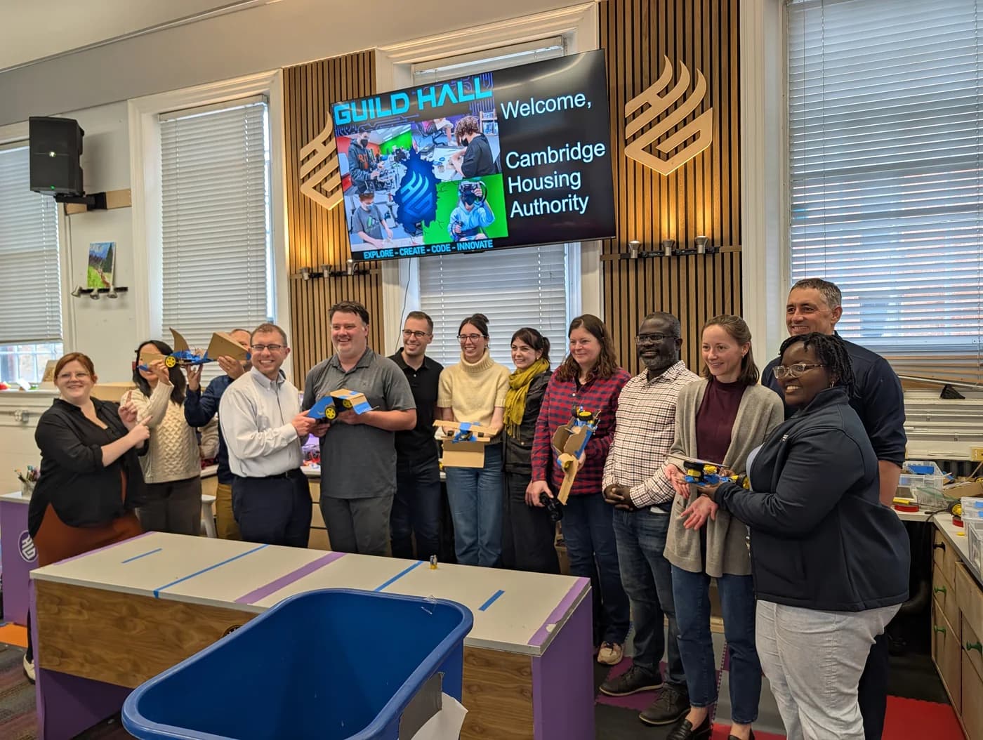 An adult workshop group holding their completed robots