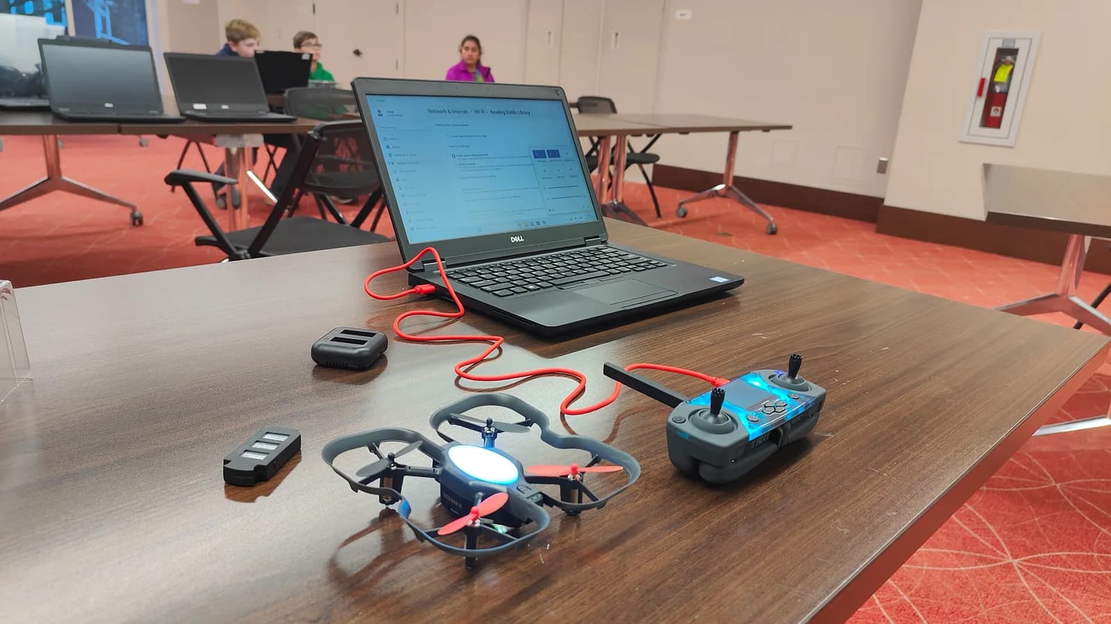 A drone, controller and laptop arranged on a library workshop table