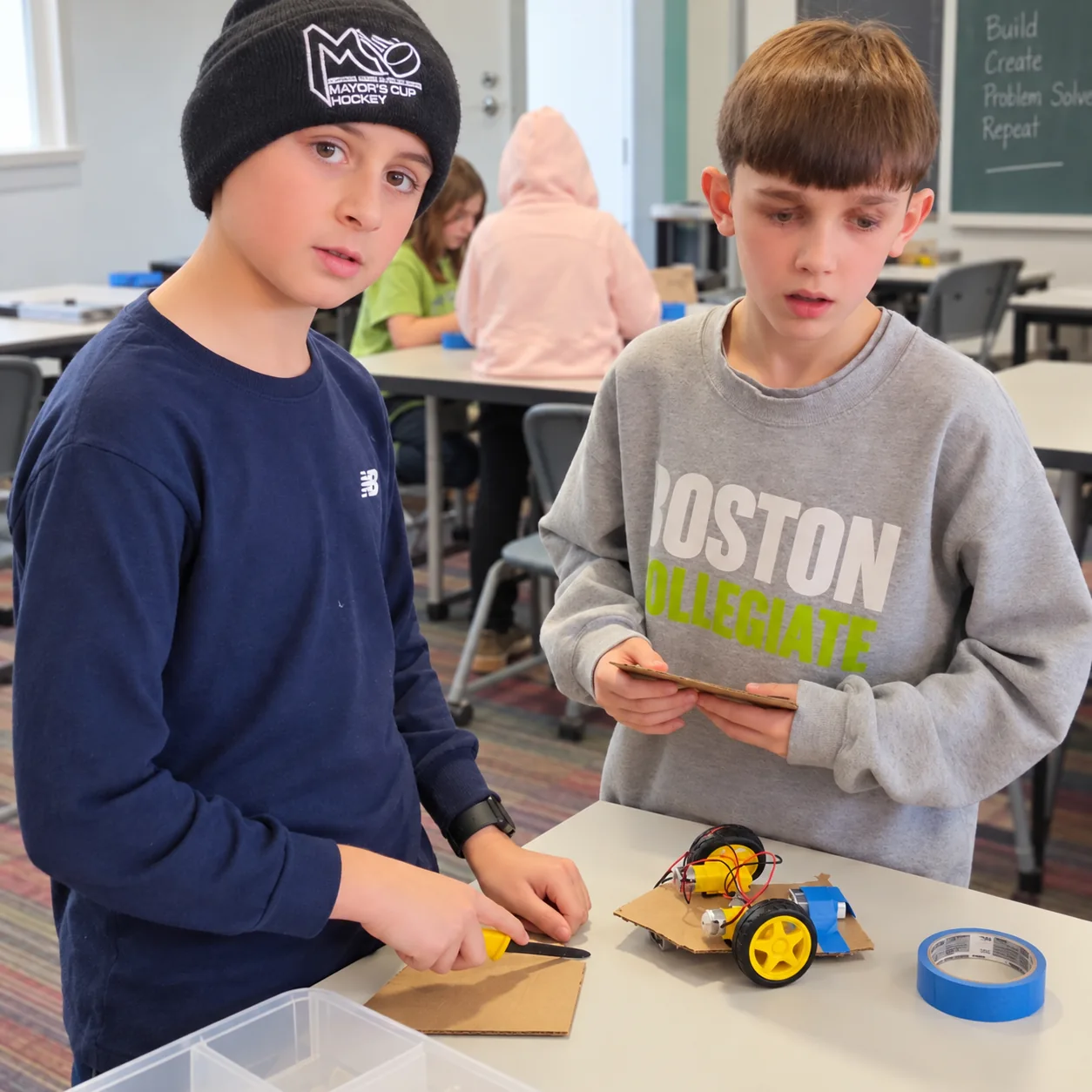 Two young makers working together on a cardboard robot